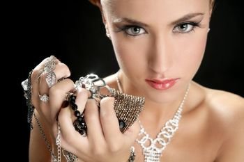 Ambition and greed in fashion woman with jewelry in hands on black background