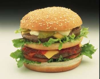 a double decker burger on a bun with salad