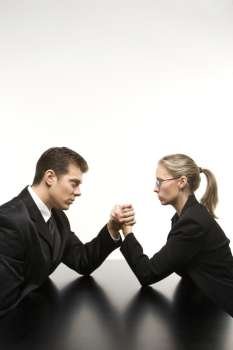 Side view of Caucasian mid-adult businessman and businesswoman arm wrestling on table