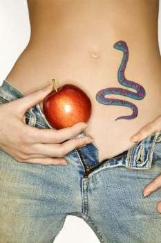 Portrait of attractive Caucasian young woman holding apple by snake tattoo on stomach