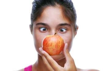 Cross Eyed Girl Looking at an Apple held in front of her face isolated over white