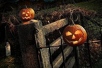 Two Halloween pumpkins sitting on fence