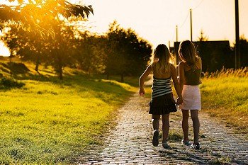 Two sister children on a path leading to the next village  dreamy evening mood in a backlit setting