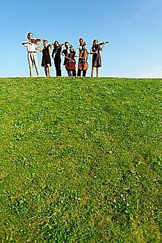 group of musicians play violins on hill against sky