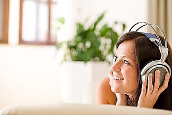 Woman with headphones listen to music in lounge  plant in background