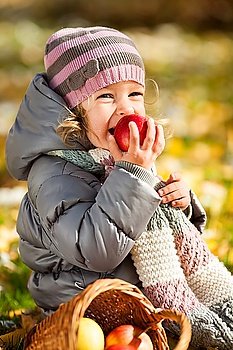 Smiling child eating red apple in autumn park Healthy lifestyles concept