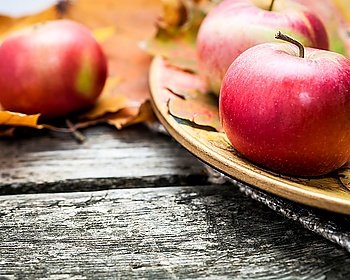 Autumn red apples and maple leaves on old wooden table Thanksgiving day concept Macro shot  very shallow depth of fields
