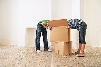 Young couple unpacking box in new home with  faces hidden