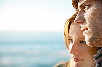 Young woman leaning on young man close up ocean and sea in background