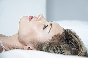 Profile of young woman in underwear lying on bed  close-up