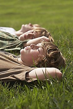 Three teenage brothers (13-17) lying down on front lawn close up