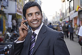 Business man using cell phone on city street  smiling