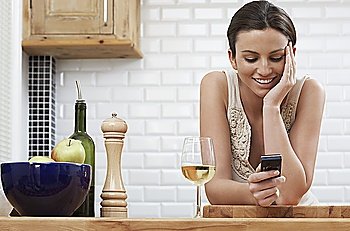 Young woman text messaging  leaning on kitchen counter