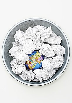 Waste bin with globe among crumpled papers  view from above
