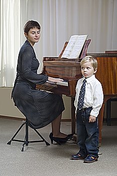 Boy (3-4) singing accompanied by teacher playing piano