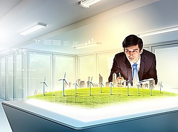 Image of young businessman looking at high-tech picture of windmills