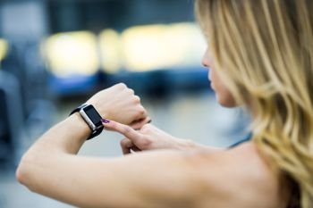 Young woman using smartwatch at the gym Caucasian female working out