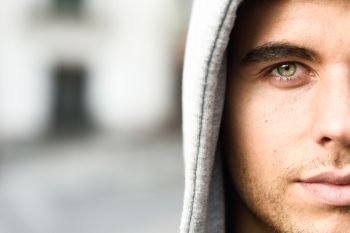 Good looking young man with blue eyes in the street wearing hooded jacket