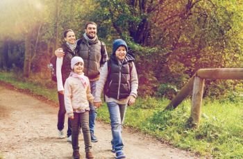travel  tourism  hike and people concept - happy family walking with backpacks along road in woods happy family with backpacks hiking in woods