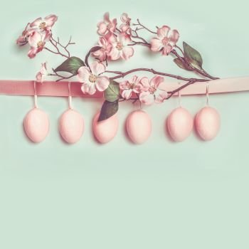 Easter greeting card layout with hanging pastel pink eggs and beautiful spring blossom decoration  copy space for your design  text  greeting or invit