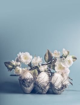 Easter concept with eggs and decorative white blossom bunch on pastel blue background  front view  copy space