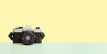Retro vintage photography camera on yellow colored background