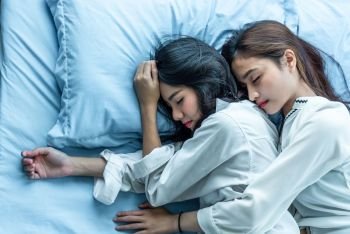 Top view of two Asian women sleeping on bed together Lesbian lovers and couple concept People and lifestyles theme