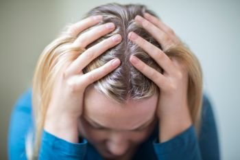 Young Woman Suffering From Depression With Head In Hands