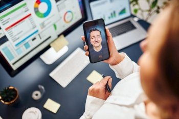 Businesswoman having video chat on mobile phone with her colleague Businesswoman working with data on charts  graphs and diagrams on computer screen