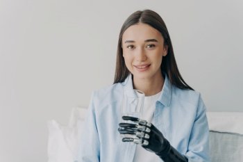 Happy disabled girl uses myoelectric hand to grasp a glass High-tech prosthesis with sensor-based nervous control Smiling European woman Technology