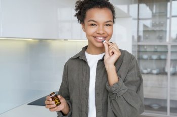 Radiant biracial girl smiles as she takes dietary supplements  vitamins  ensuring healthy skin and hair for a confident appearance