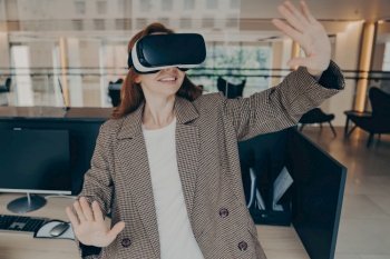 Smiling businesswoman in casual clothes dodging in VR  immersed in digital world with portable glasses  empty office