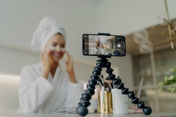 Beauty blogger records under-eye patch tutorial  tackles wrinkles and dark circles  focused on smartphone  bathrobe attire