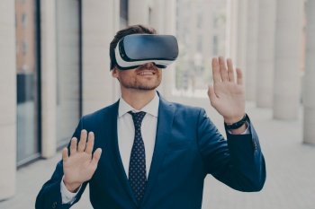 Excited businessman in suit on city street  testing VR glasses for the first time  gesturing and touching objects in air