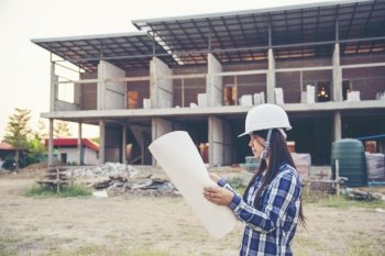 Woman construction engineer hold blueprint wear plaid shirt safety white hard hat at construction site industry labor worker Architecture Female engi