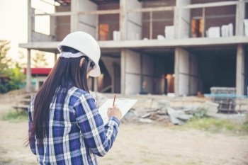Woman construction engineer writing note wear plaid shirt safety white hard hat at construction site industry labor worker Architecture Female design