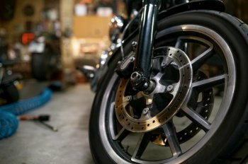 Closeup view on motorcycle front wheel in workshop Motorbike showroom for sale or repair garage service concept Closeup on motorcycle wheel in works