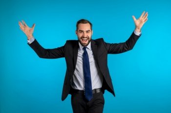 Surprised excited happy businessman on blue background Man shows yeah gesture of victory  he achieved result  goals Surprised excited happy business
