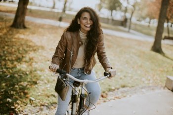 Pretty young woman riding bicycle on autumn day