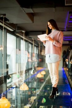 Woman standing on the glass floor with tablet in the hand