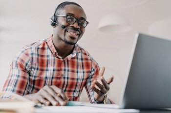 Friendly manager of client support service African american man in headset receives calls Online shop assistant is working from home Teacher has re