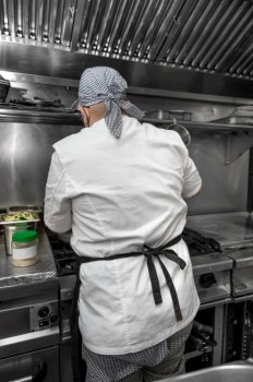 Back view of woman chef cooking food in the kitchen of a restaurant High quality photography Back view of woman chef cooking food in the kitchen of