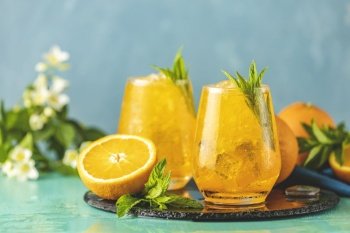 Two glass of orange ice drink with fresh mint on wooden turquoise table surface Fresh cocktail drinks with ice fruit and herb decoration Alcoholic n