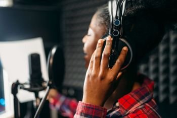 Young woman in headphones songs in audio recording studio Musician listens composition  professional music mixing Young woman songs in audio recordi