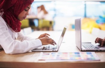 Young modern black muslim business woman wearing a red hijab working on laptop computer in startup office Diversity  multiracial concept