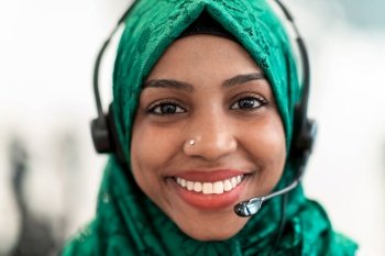 Afro Muslim female with green hijab scarf customer representative businesswoman with phone headset helping and supporting online with the customer in 