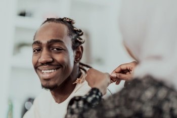 A young Muslim couple has a romantic time at home while the woman makes the hairstyle for her husband female wearing traditional Sudan Islamic hijab c