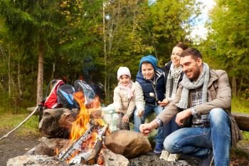 camping  travel  tourism  hike and people concept - happy family roasting marshmallow over campfire happy family roasting marshmallow over campfire