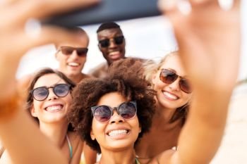 friendship  summer holidays and people concept - group of happy friends taking picture by smartphone on beach happy friends taking selfie on summer b