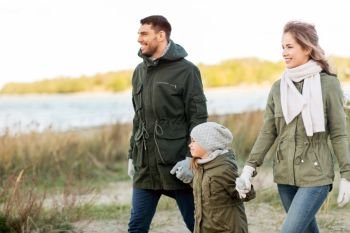 family  leisure and people concept - happy mother  father and little daughter walking along autumn beach happy family walking along autumn beach